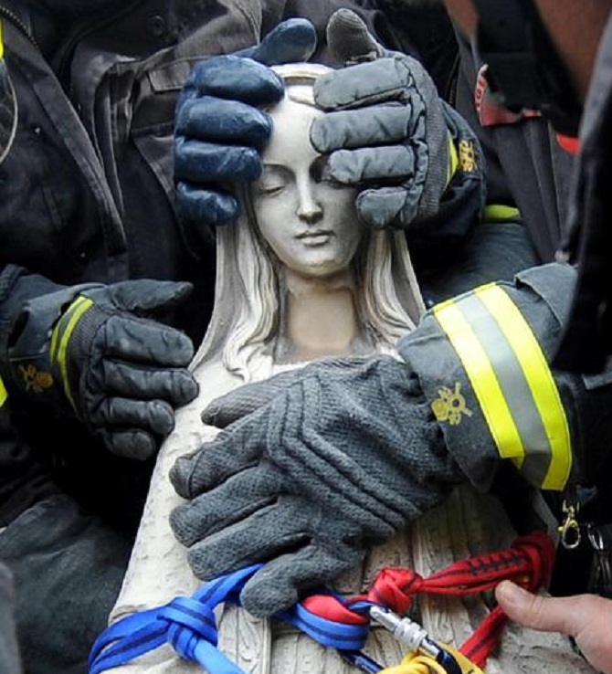 Le mani dei Vigili del Fuoco proteggono la statua della Madonna rimossa dalla facciata pericolante della chiesa di Paganica (L'Aquila) recuperata dalle macerie del terremoto del 6 aprile 2009