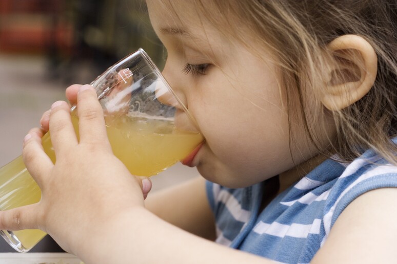 bambina beve un succo di frutta