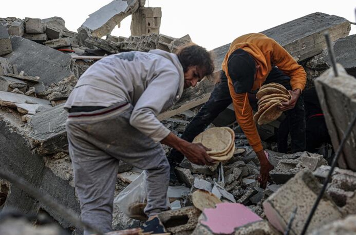 Due palestinesi raccolgono del cibo tra le rovina di Gaza FOTO ANSA