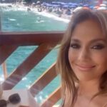 Jennifer Lopez sorridente al tavoli di un ristorante sullo sfondo di Capri