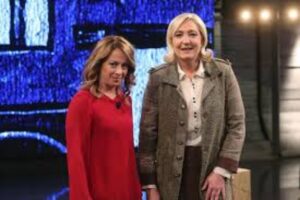 Giorgia Meloni in cappotto rosso e Marine Le Pen che vincerà le elezioni in Francia, in beige sorridenti, 