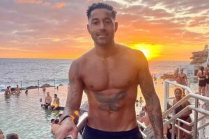 Govind Sandhu quando era un giovane atletico a torso nudo con tatuaggio su una spiaggia: ma la vita gli preparava un brutto scherzo