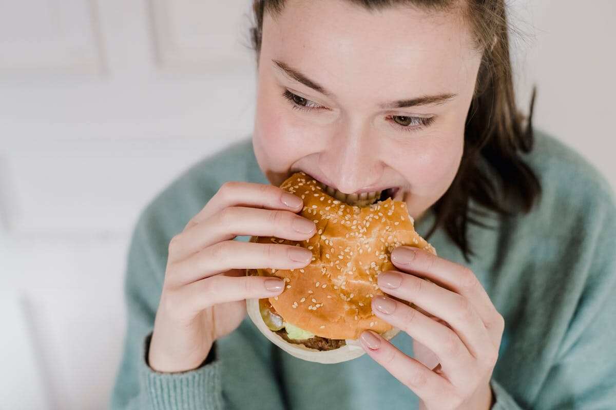 giovane donna mangia un hamburger