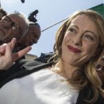 Giorgia Meloni a un raduno di partito con bandiera