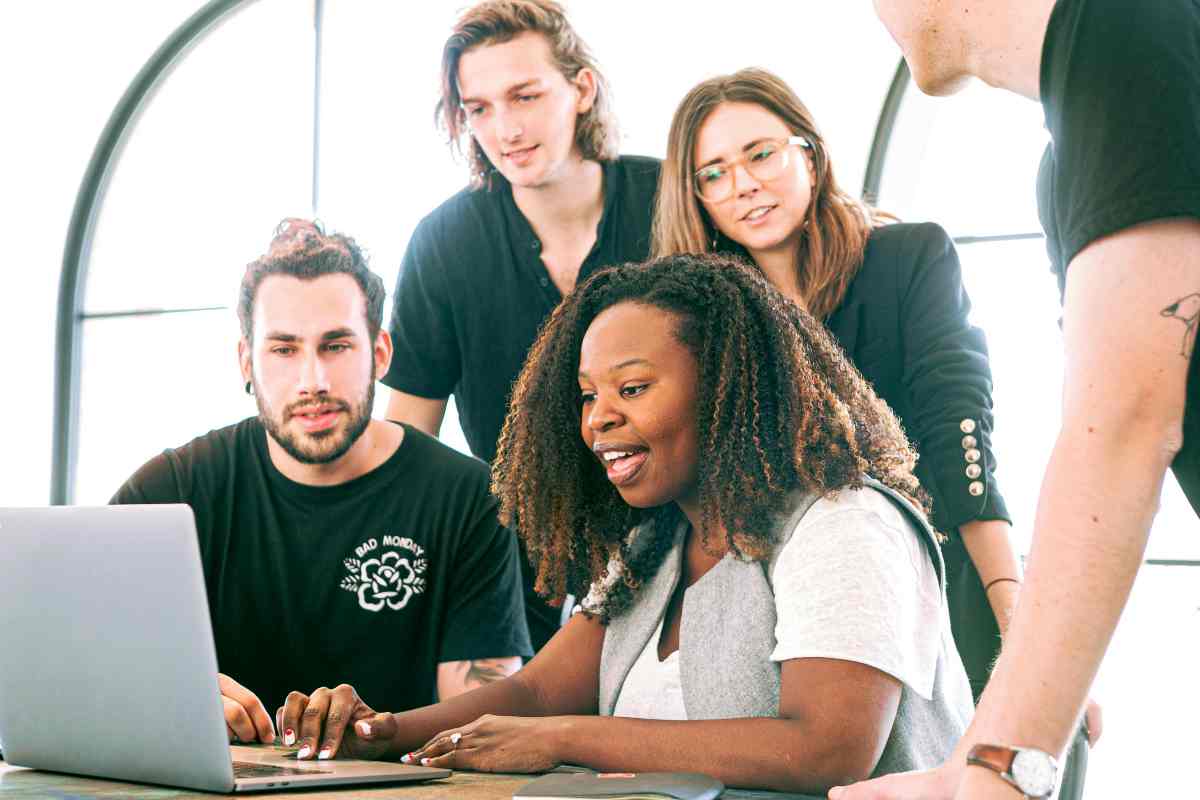 Quattro giovani lavoratori di fronte a un laptop