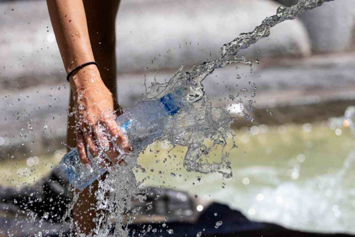 Persona riempie bottiglia acqua