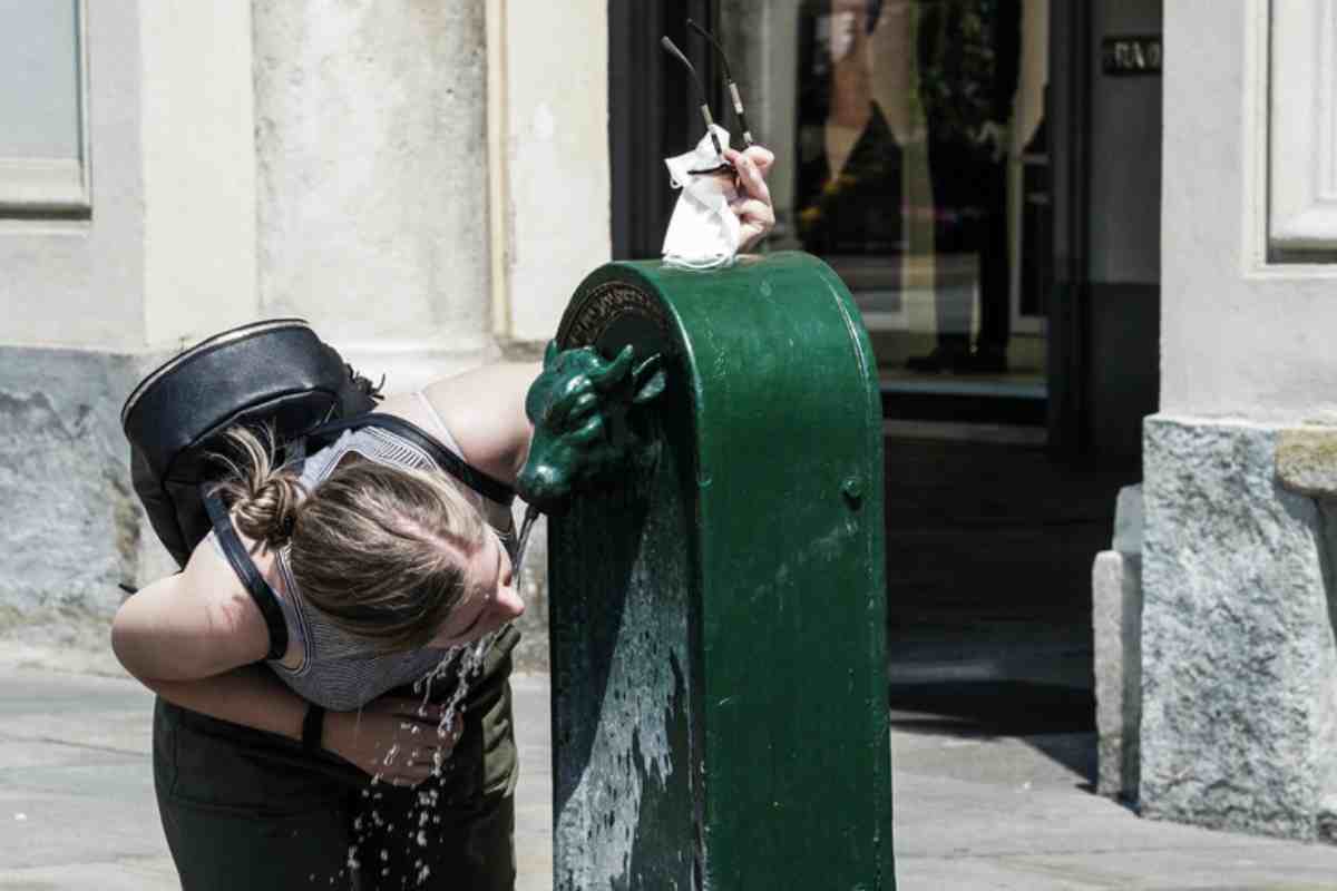 Ragazza beve acqua alla fontanella