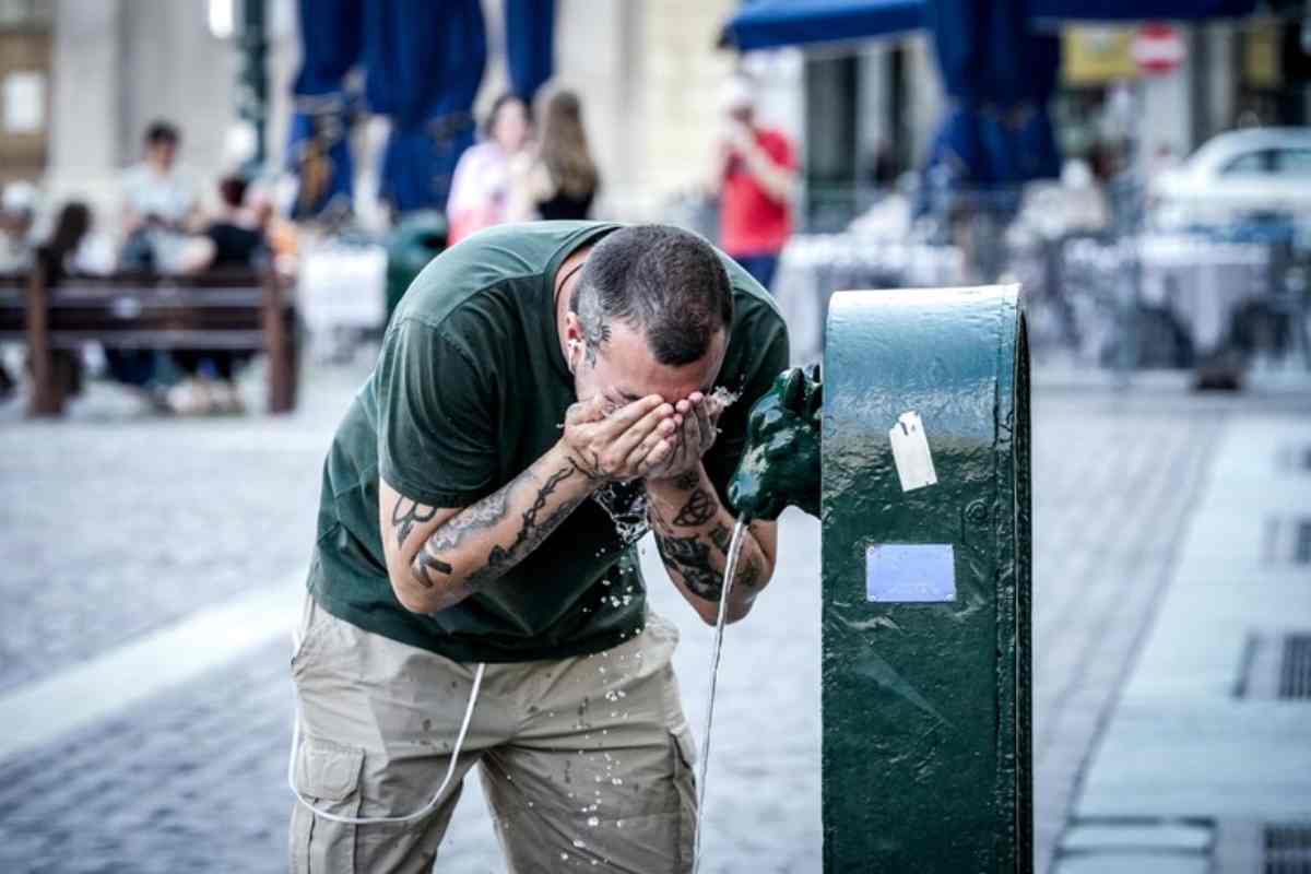 Un uomo beve alla fontanella per il gran caldo