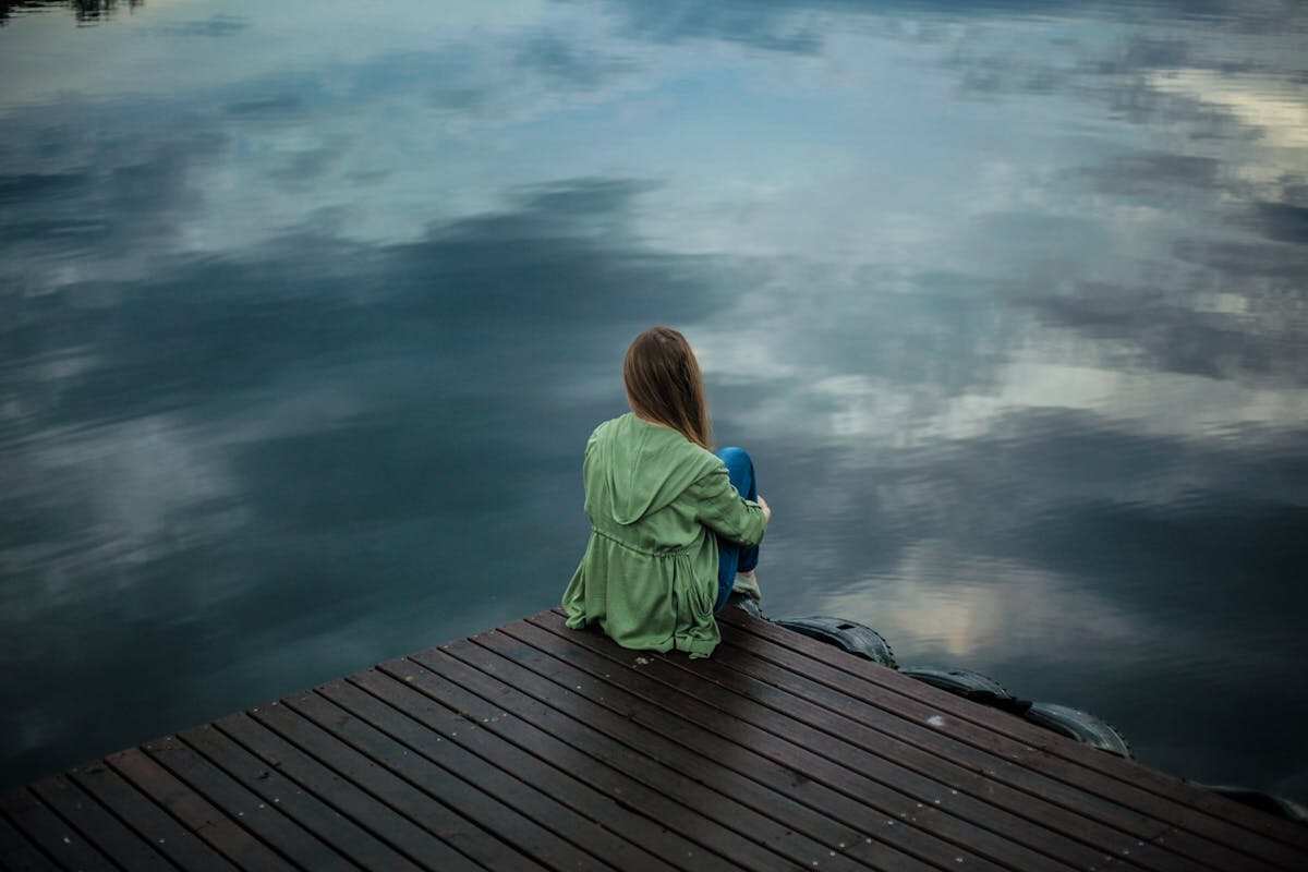 ragazza seduta davanti un lago