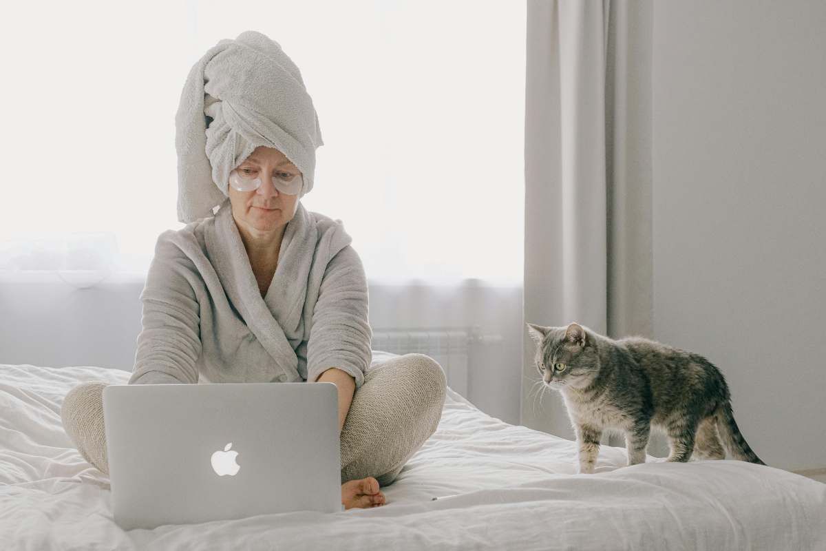 Donna al portatile sul letto con gatto