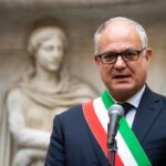 Roberto Gualtieri con fascia tricolore da sindaco di Roma parla a un microfono in Campidoglio