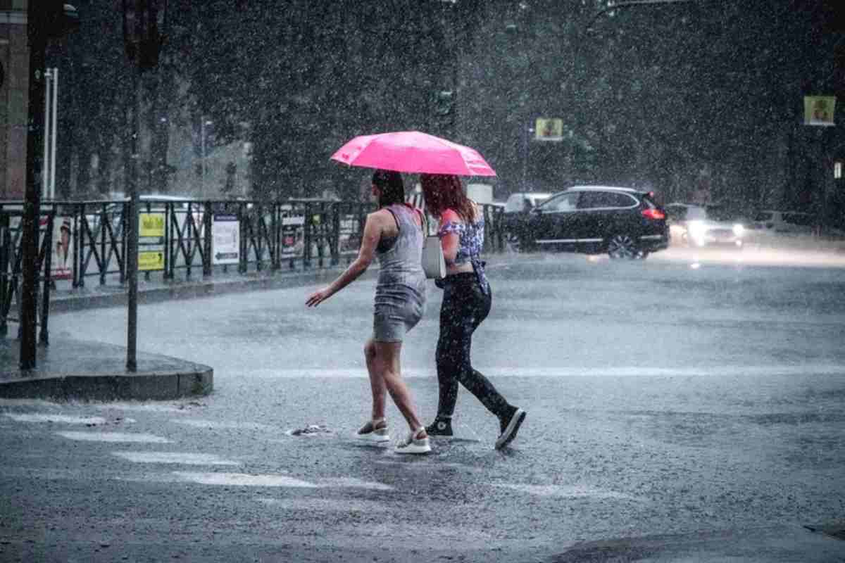 Gente cammina in estate sotto la pioggia