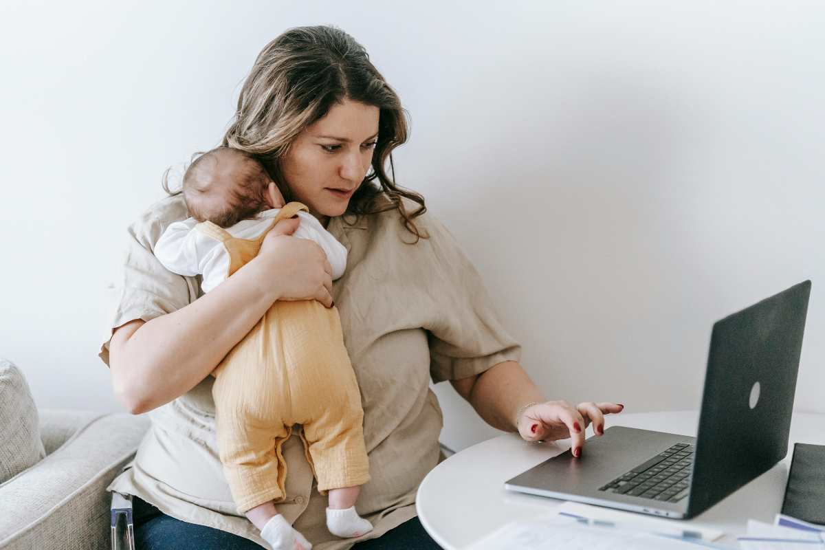 Mamma con neonato che lavora al computer