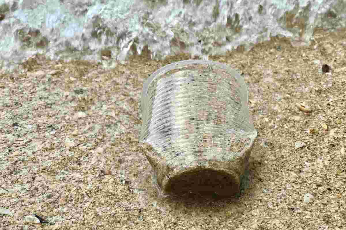 un bicchiere di plastica che inquina la spiaggia