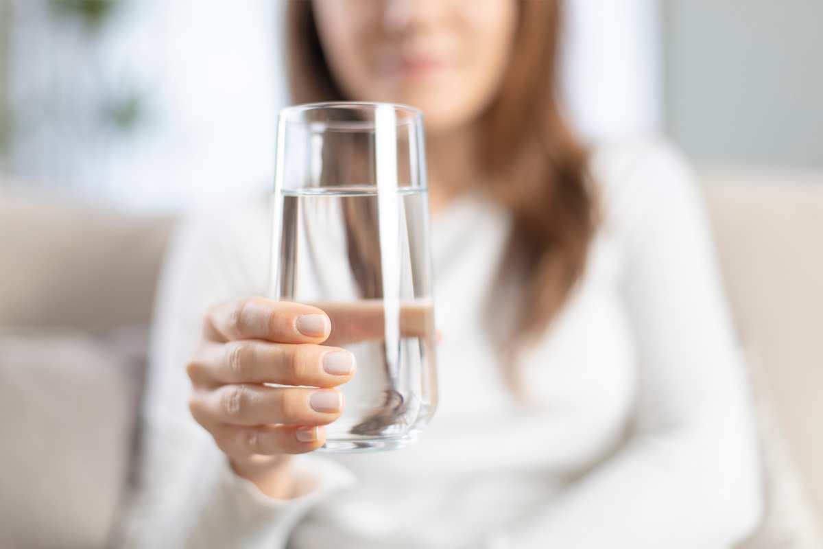 donna con un bicchiere di acqua minerale in mano come simbolo di bere ogni giorno