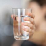 persona tiene un bicchiere di acqua in mano come simbolo di Cosa succede se non beviamo acqua per due giorni