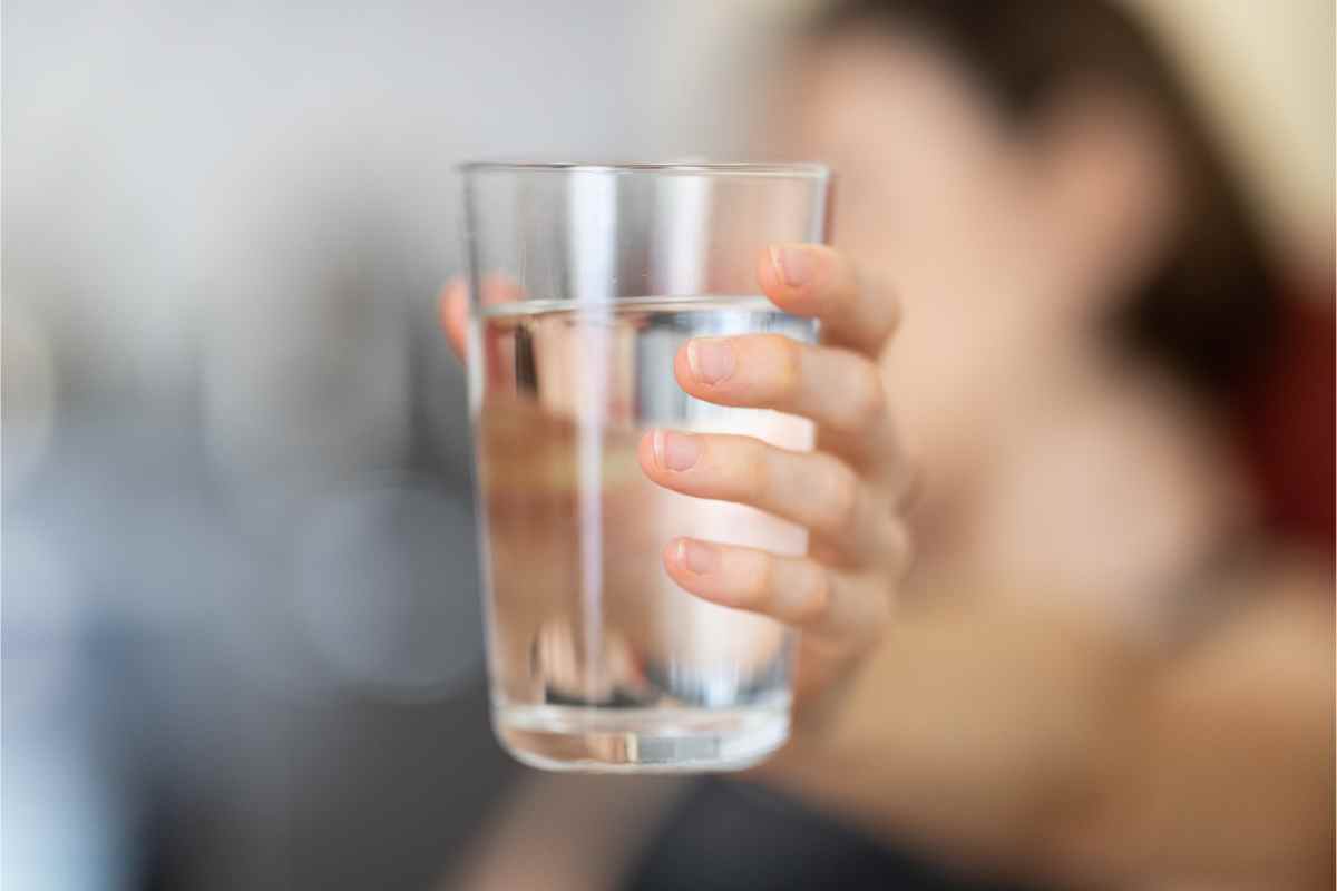 persona tiene un bicchiere di acqua in mano come simbolo di Cosa succede se non beviamo acqua per due giorni