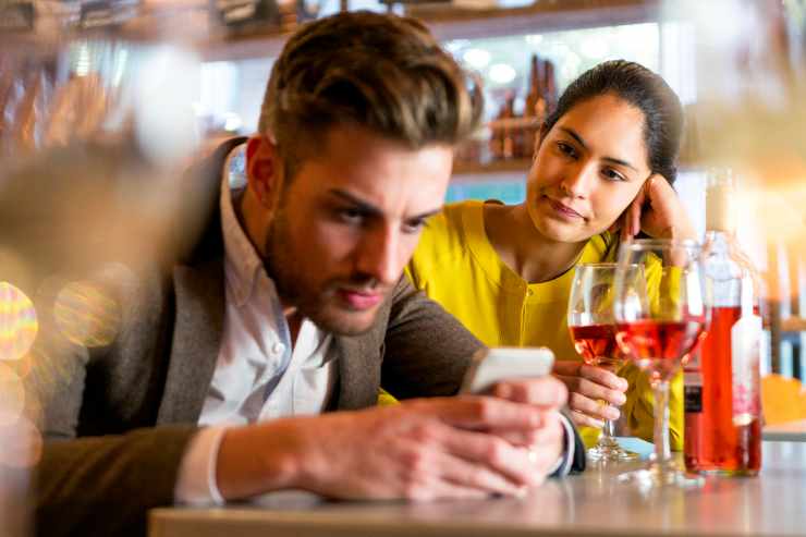 ragazzo guarda lo smartphone ignorando la ragazza dietro