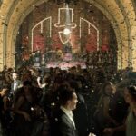 fotogramma dalla serie Babylon Berlin. Una folla vestita in stile anni Venti balla in un nightclub con la band che suona sul palco sullo sfondo.