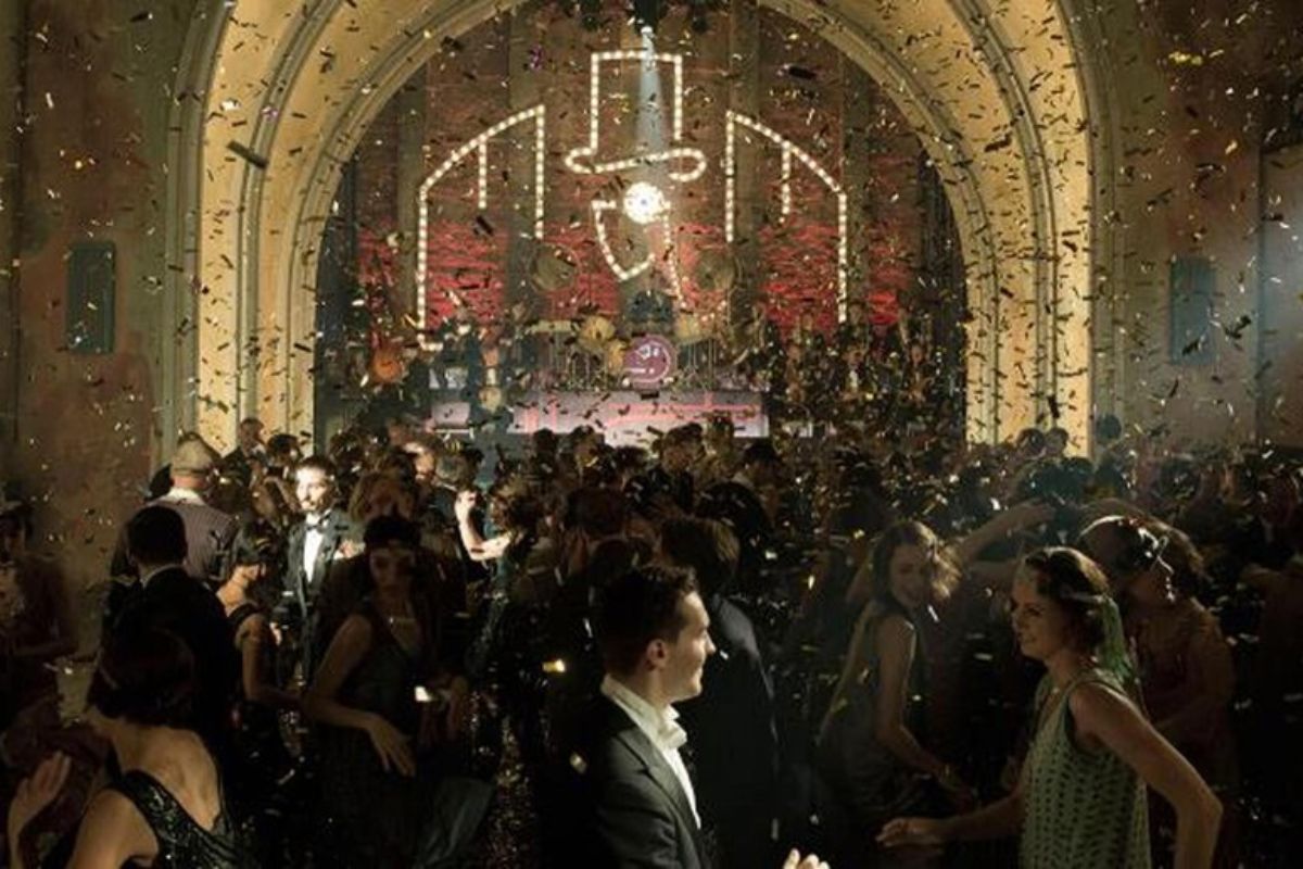 fotogramma dalla serie Babylon Berlin. Una folla vestita in stile anni Venti balla in un nightclub con la band che suona sul palco sullo sfondo.