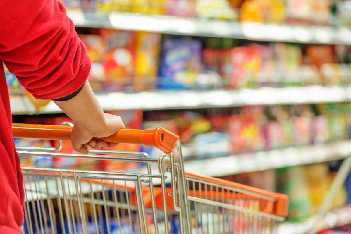 una persona spinge un carrello in una corsia del supermercato