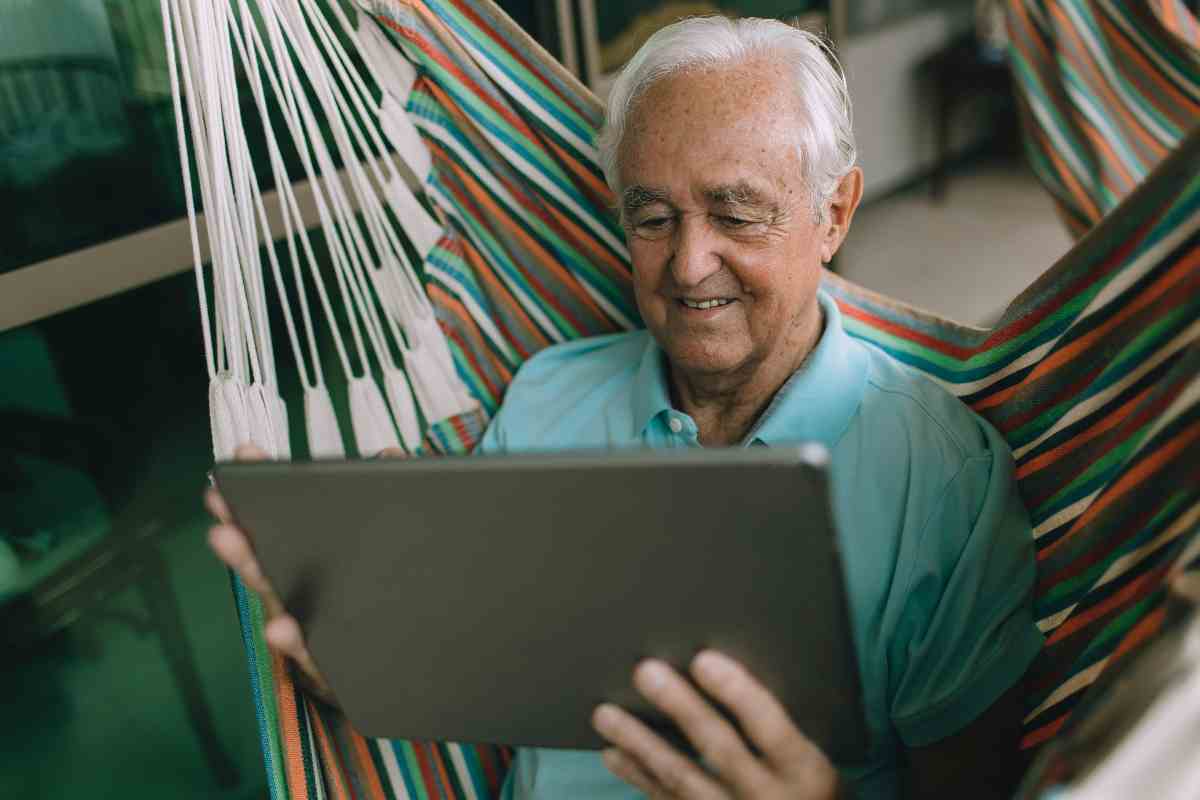 Anziano con un tablet su un'amaca