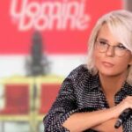 maria de filippi in primo piano con lo studio di uomini e donne sullo sfondo