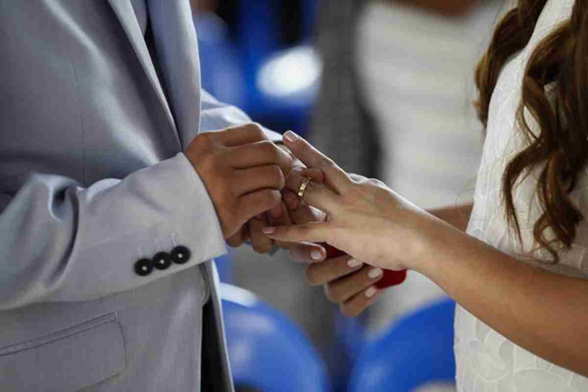 Dettaglio di un matrimonio, con le mani degli sposi nel momento dello scambio delle fedi