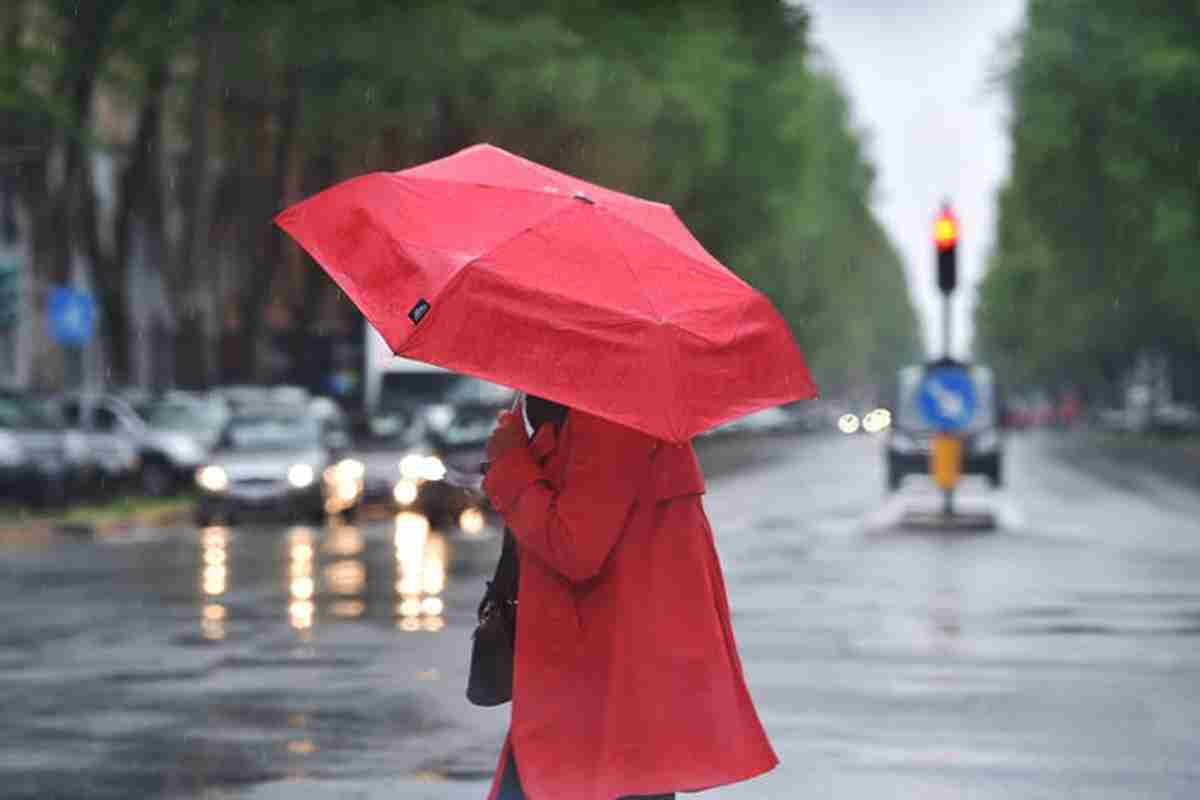 Una persona di rosso vestita con un ombrello di rosso colorato