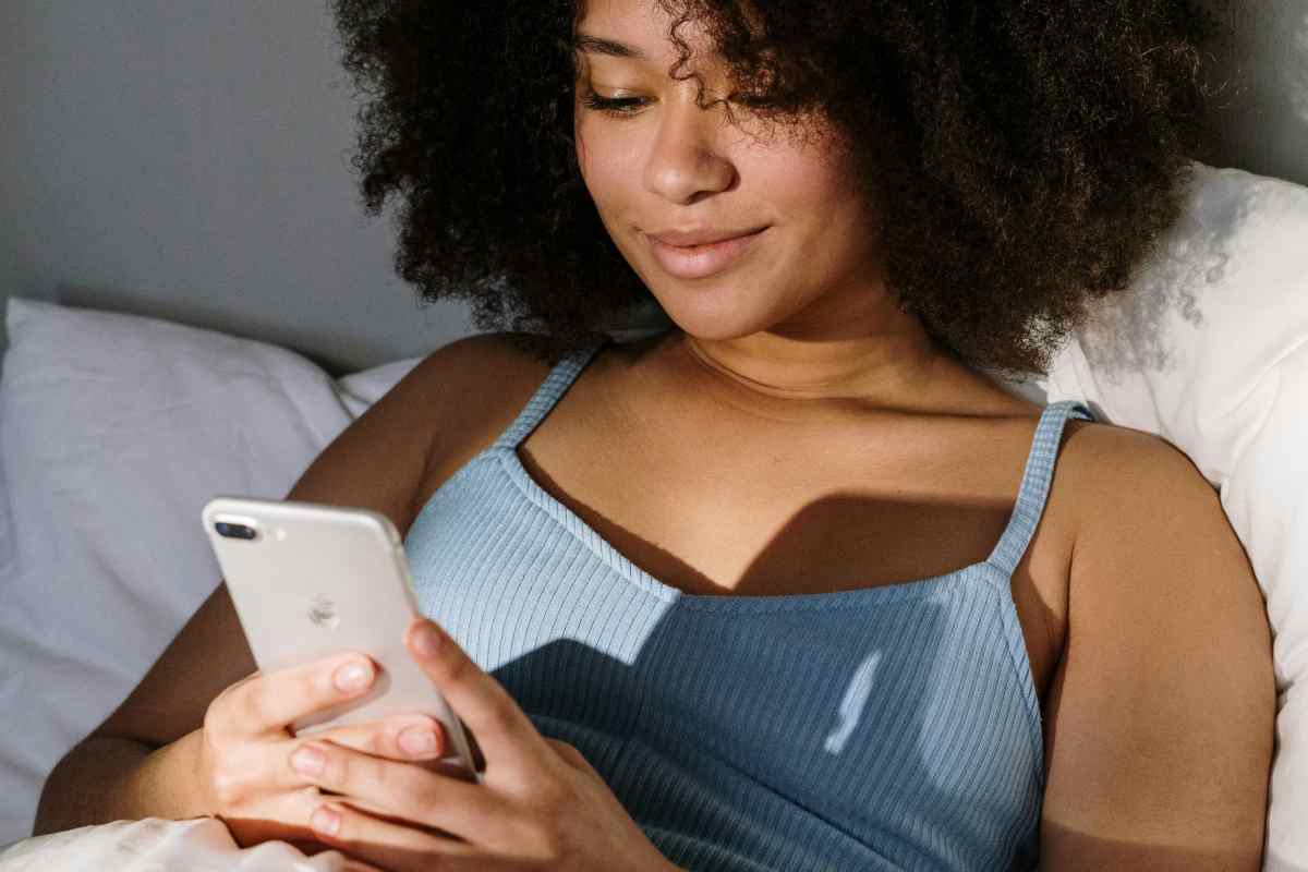 Ragazza con lo smartphone sul letto