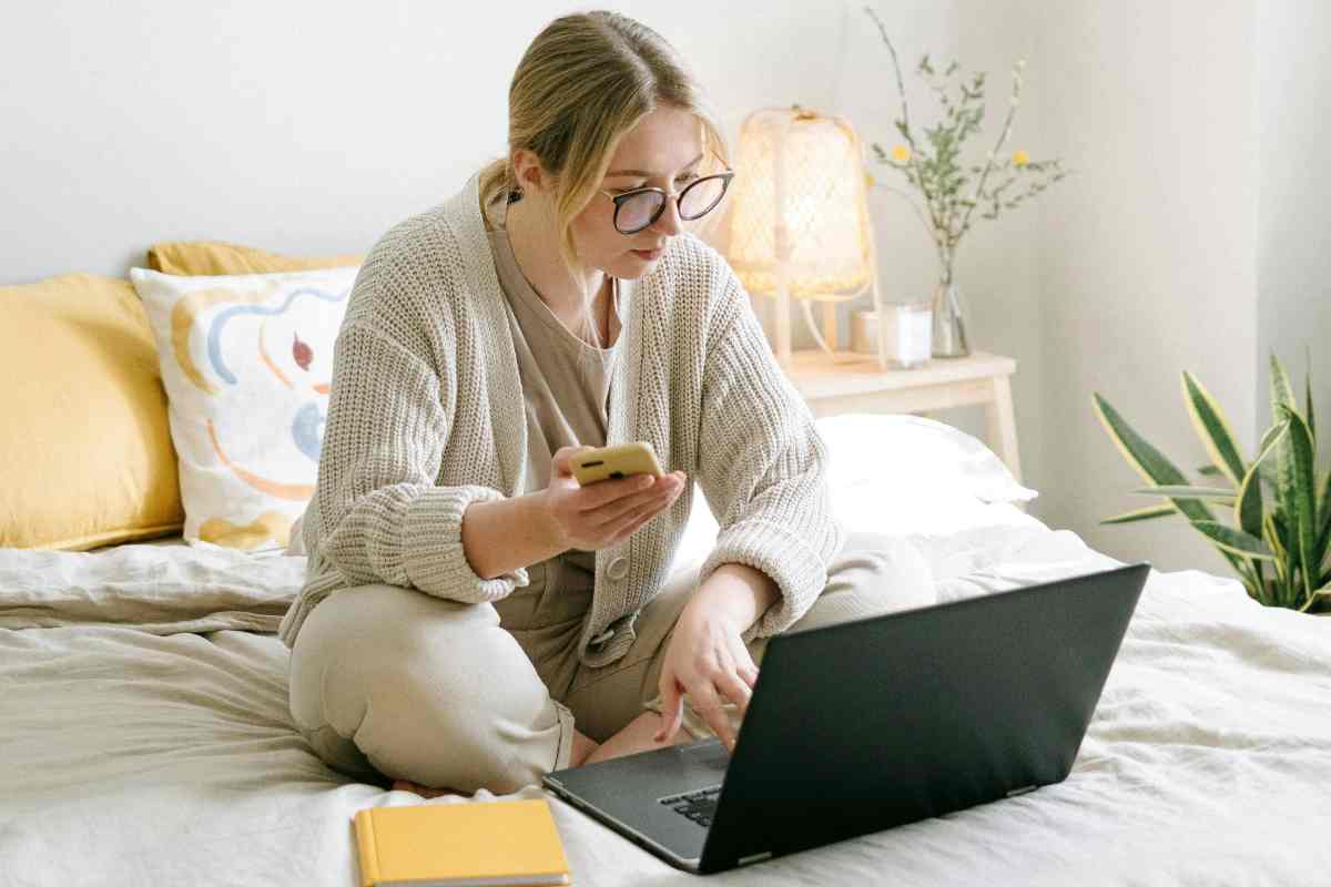 Ragazza seduta sul letto che guarda un portatile