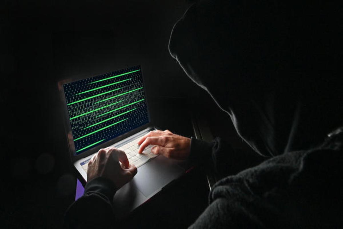 Hacker in azione con il suo computer, in una stanza illuminata solo dal monitor