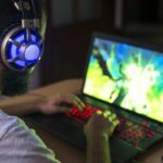 Un ragazzo con le cuffie gioca a un videogioco sul computer