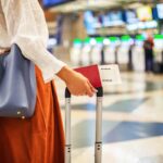 Una donna all'aeroporto di profilo con un trolley e la carta d'imbarco in mano