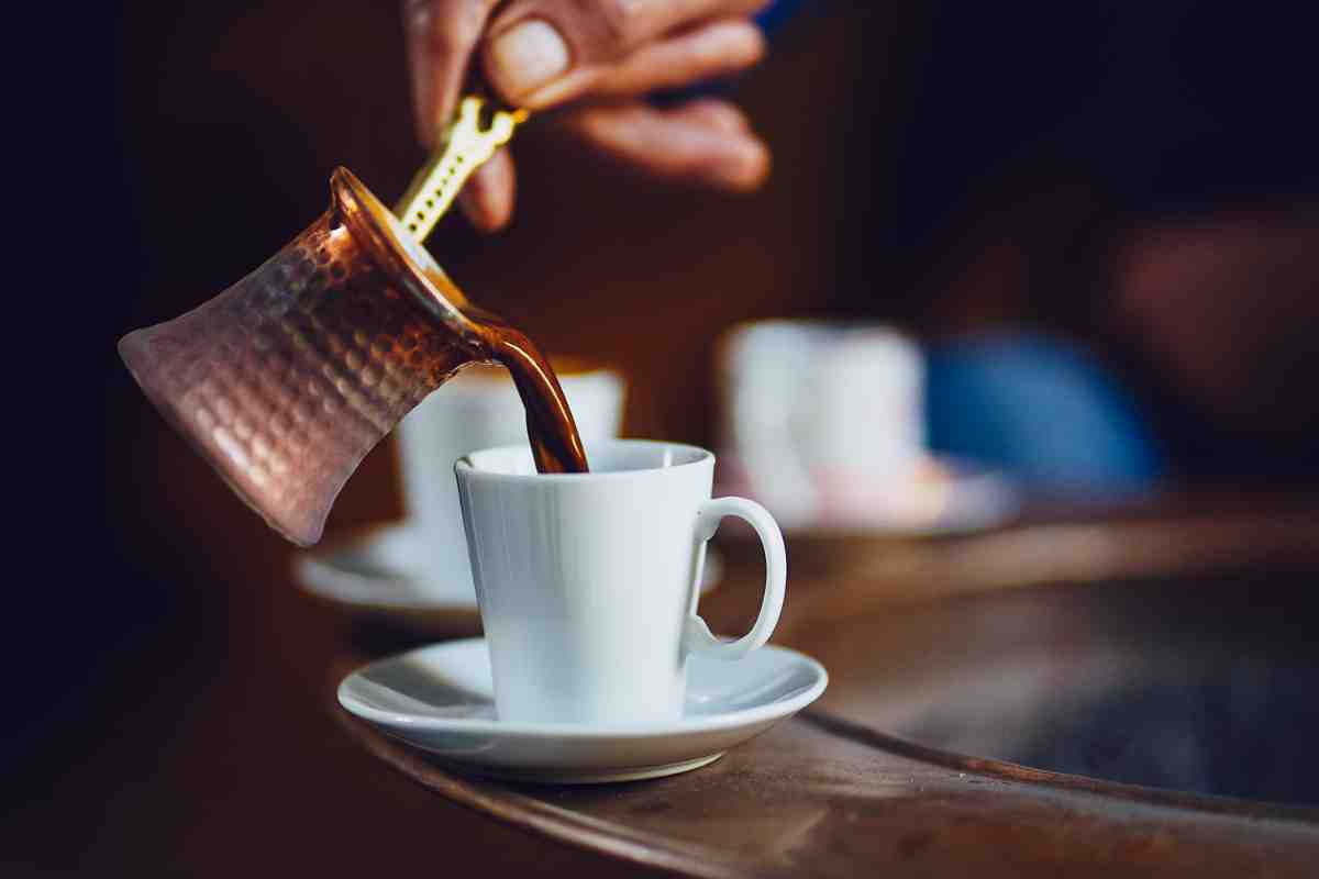 Caffè senza macchinetta con il metodo turco versato dal pentolino nella tazzina