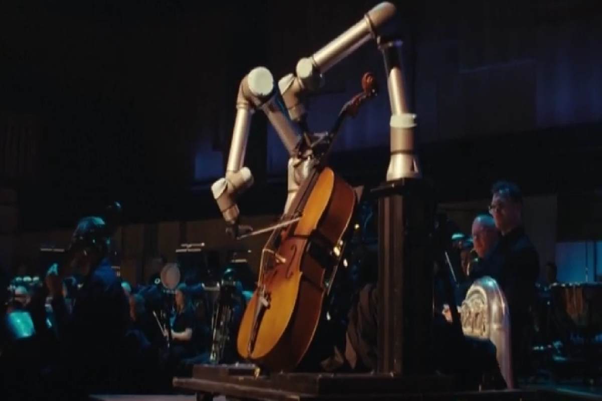 Un robot con lunghe braccia meccaniche che suona il violoncello e l'orchestra sullo sfondo