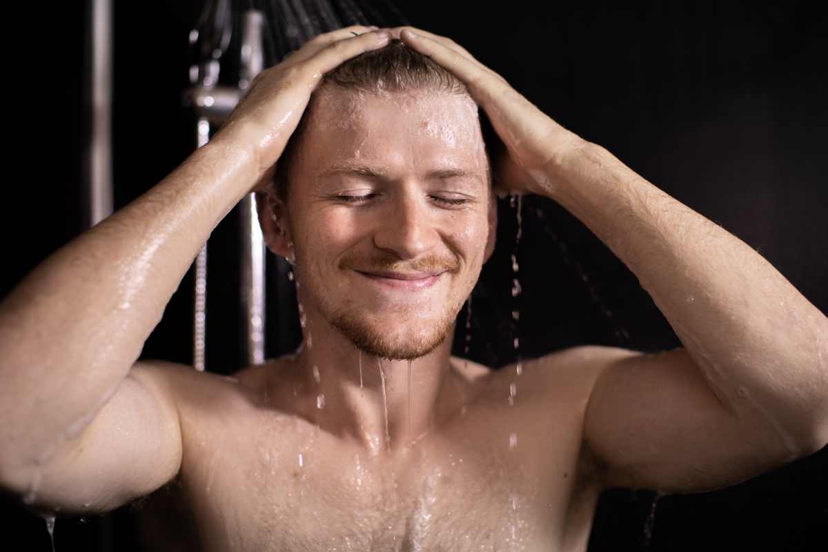 uomo sotto la doccia fa lo shampoo