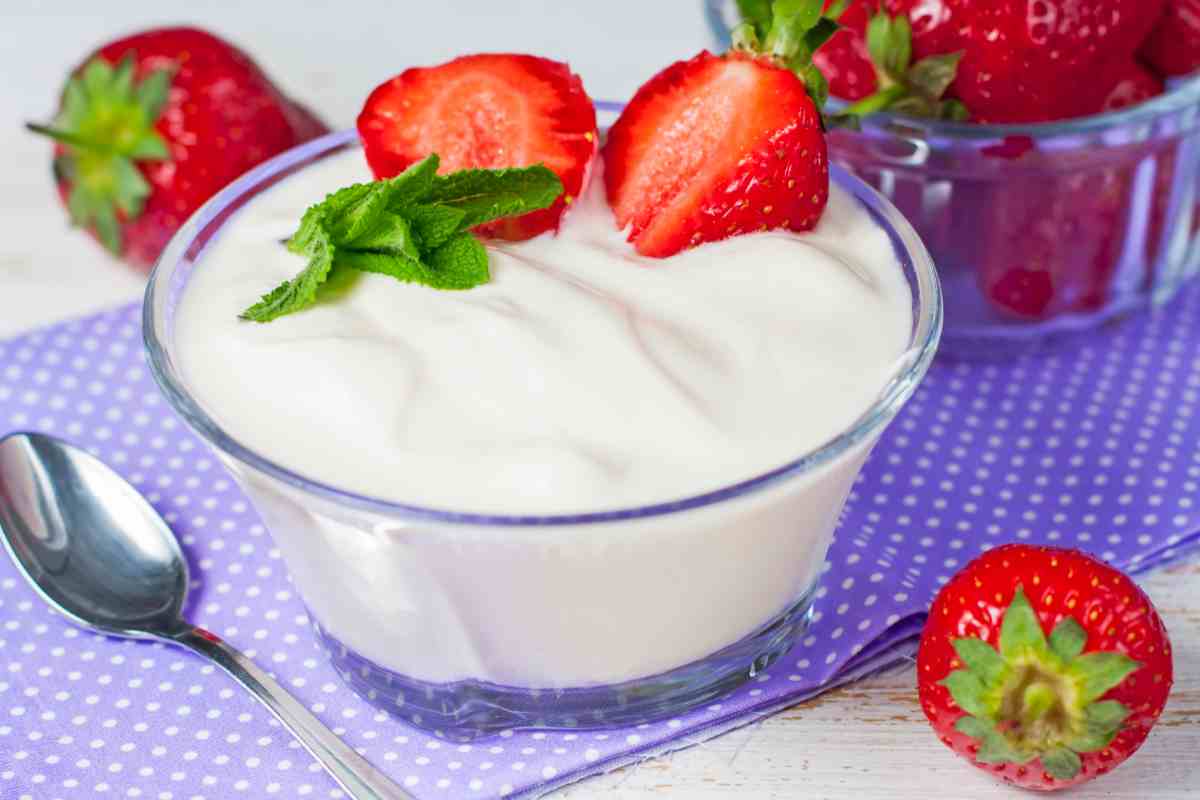 Yogurt fatto in casa in un vasetto con fragole come guarnizione