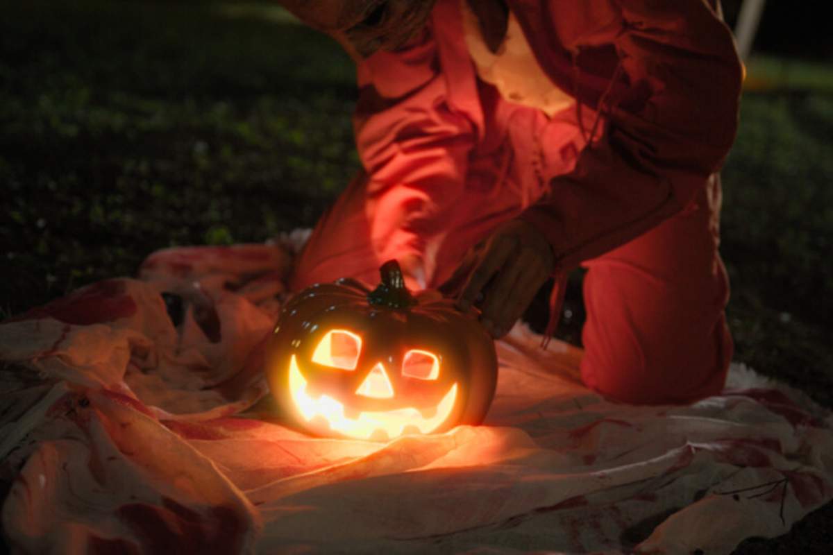 Una ragazzo sistema una tradizionale zucca illuminata per la festa di Halloween