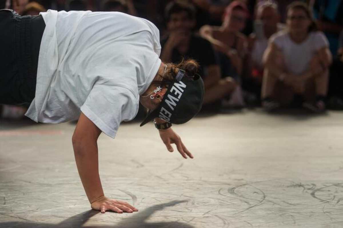 uomo con berretto nero che fa breakdance con pubblico in sala