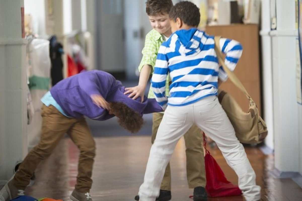 bambini che picchiano un compagno nei corridoi della scuola