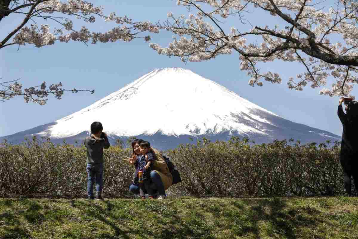 L'iconico Monte Fuji in Giappone sullo sfondo, in primo piano una famiglia che lo fotografa