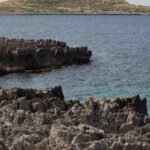 Panoramica di alcuni scogli, il mare e un'isola sullo sfondo