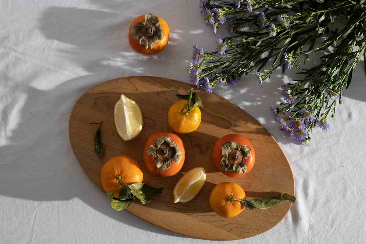 dei cachi e degli agrumi sopra ad un tagliere di legno