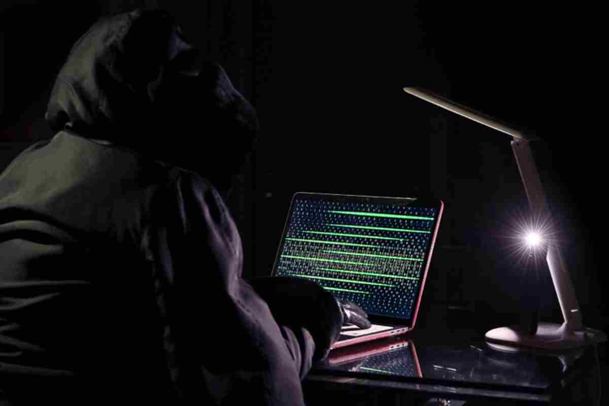 Un uomo incappuciato davanti ad un pc a rappresentare un hacker