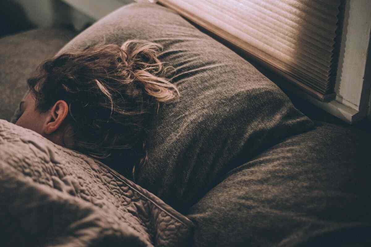 una ragazza dorme dentro a un letto con i capelli legati