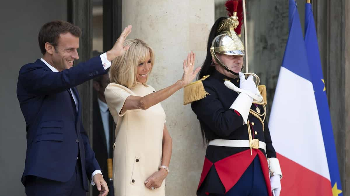 Emmanuel Macron e la moglie Brigitte salutano vicino a un corazziere