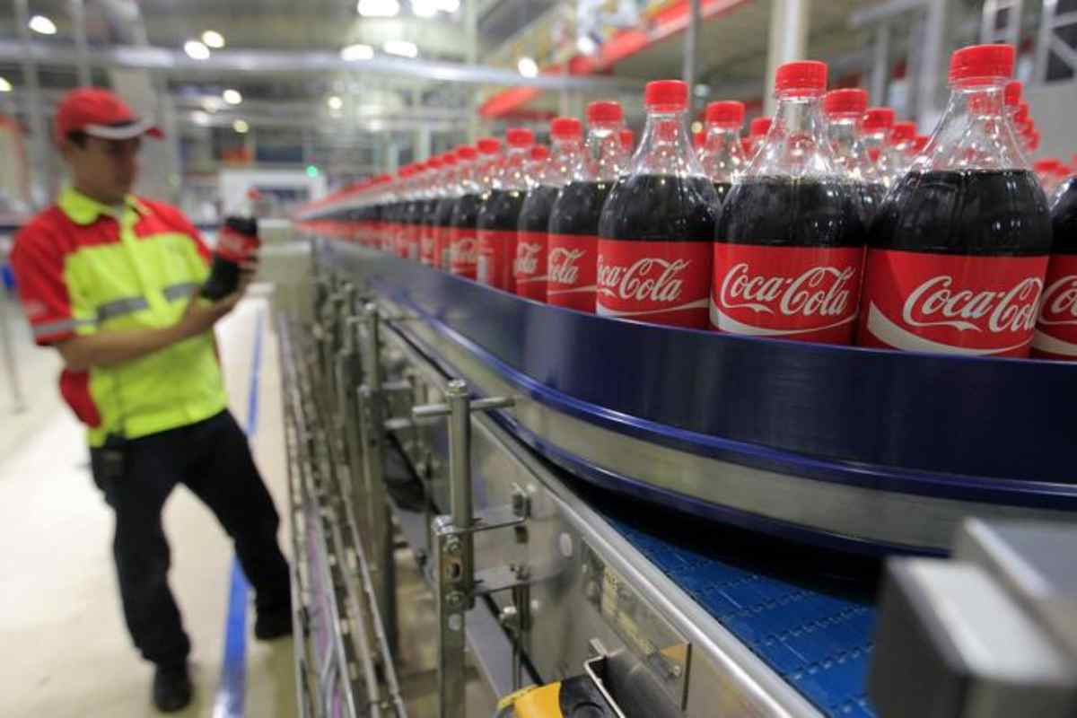 Bottiglie in plastica di Coca-Cola nel corso del processo di produzione, con un addetto sullo sfondo