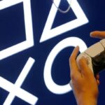 Le mani di un ragazzo sul controller della PS5, sullo sfondo il logo di Play Station