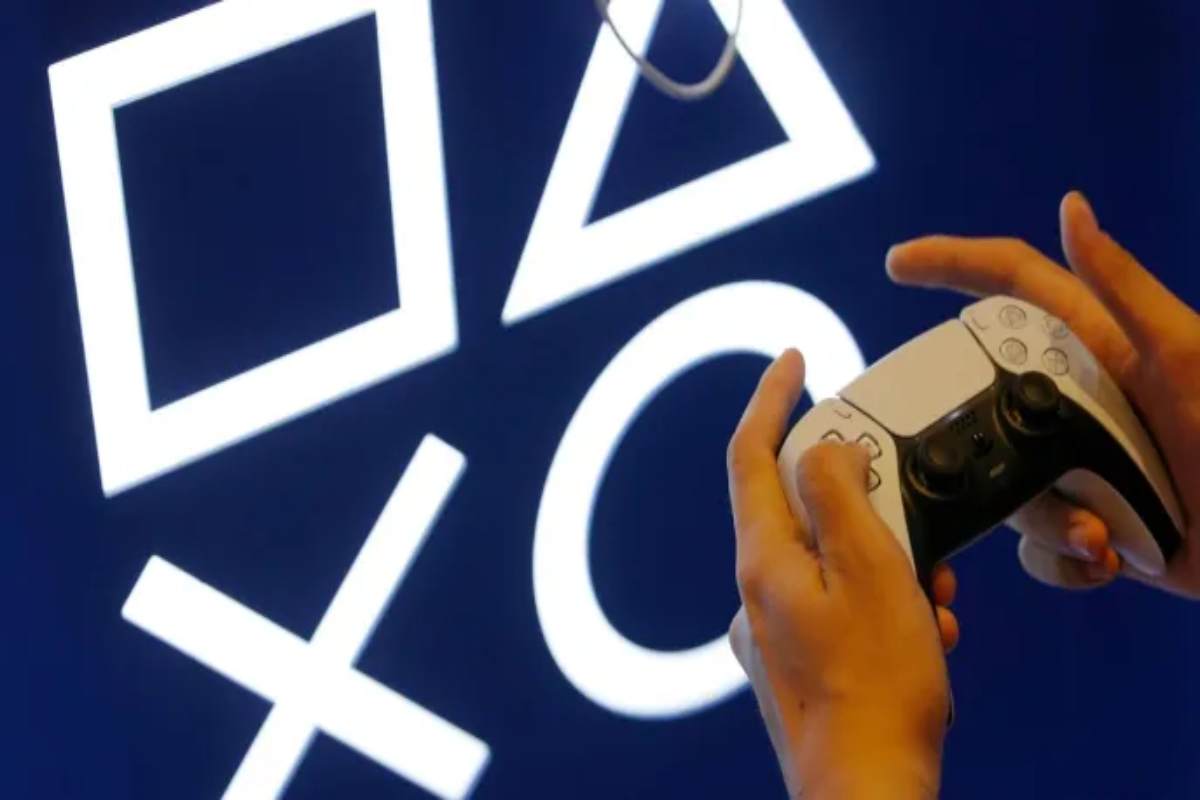 Le mani di un ragazzo sul controller della PS5, sullo sfondo il logo di Play Station